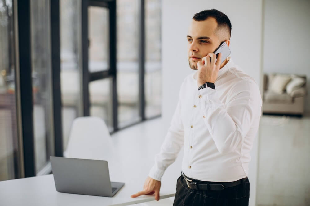 mlody-mezczyzna-rozmawiajacy-przez-telefon-w-biurze